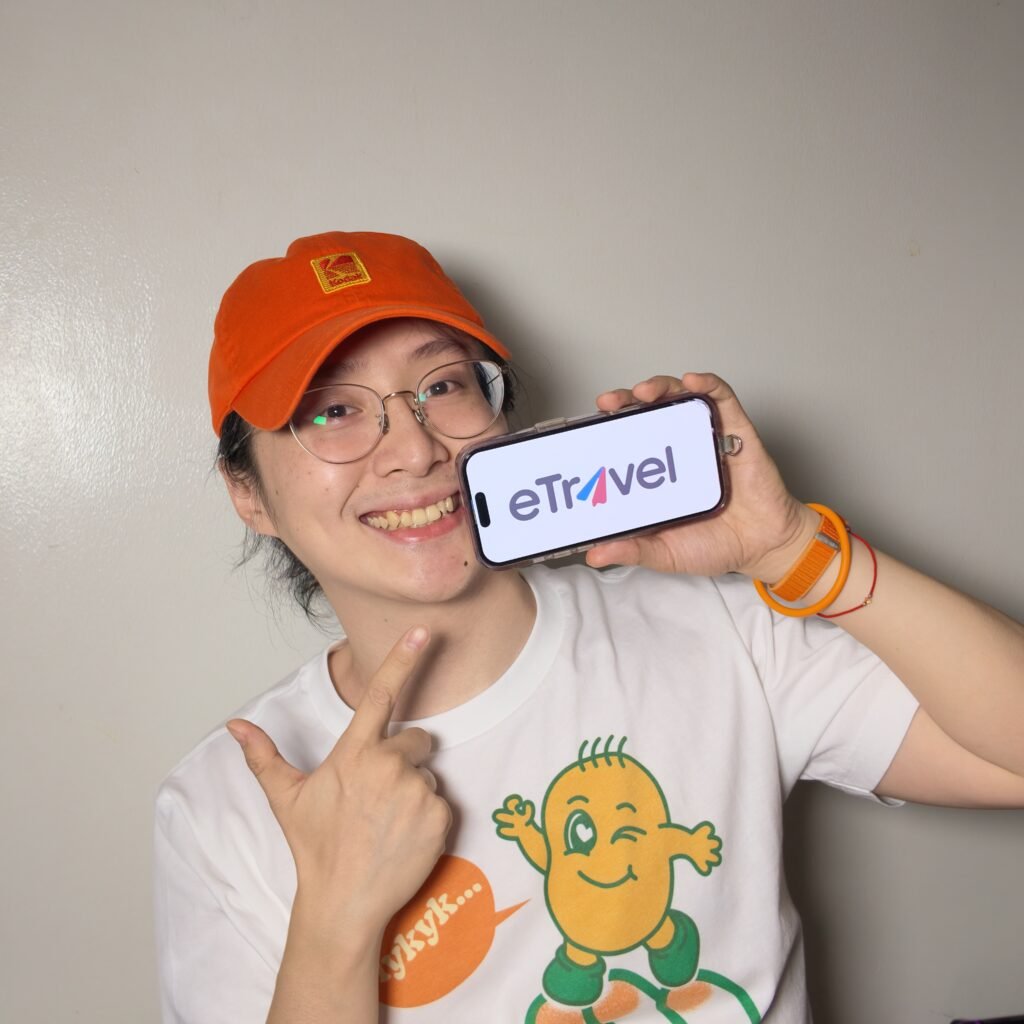 小凱戴橘色帽子拿著顯示 eTravel 標誌的手機