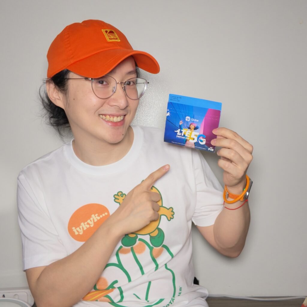 小凱戴橘色帽子手持 Globe 5G 預付 SIM 卡